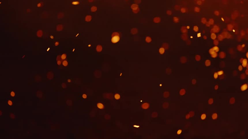Closeup of burning embers with smoke flying in slow motion at night