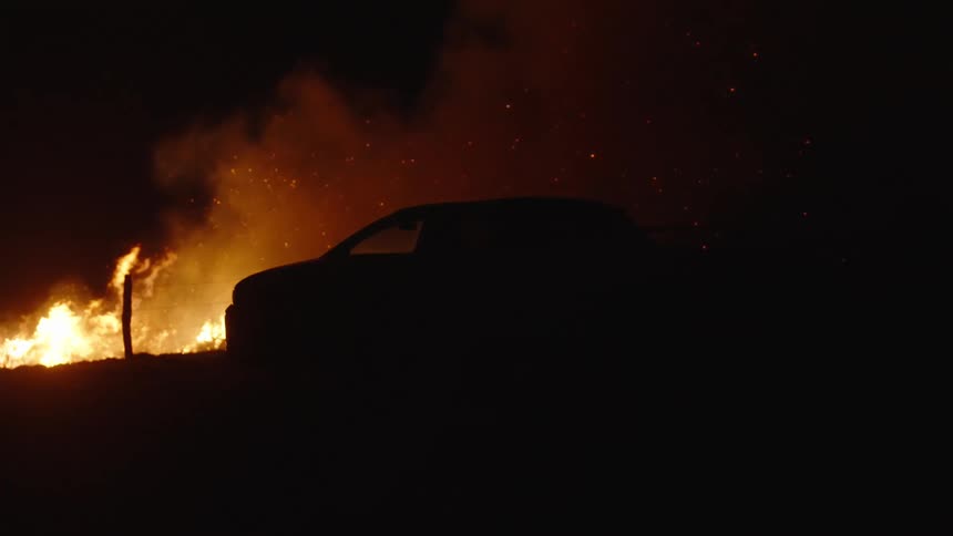 Car engulfed in flames in the midst of a forest at night