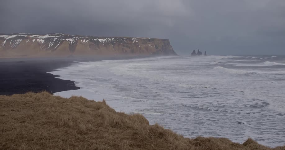 Ocean waves foam on a black sand beach