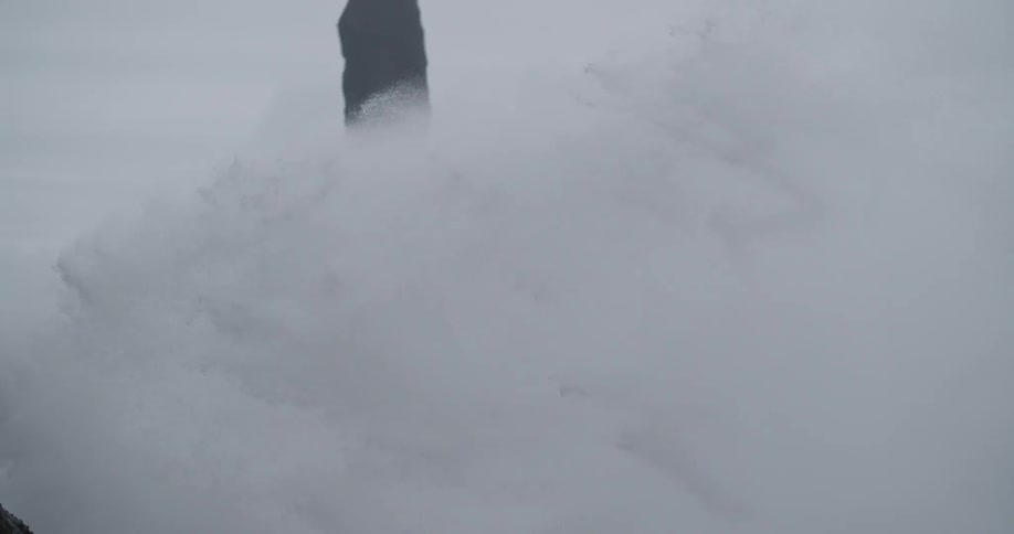 Heavy waves crash against the rocks spraying water everywhere