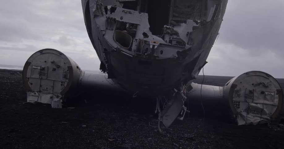A large downed plane is sitting under a cloudy sky