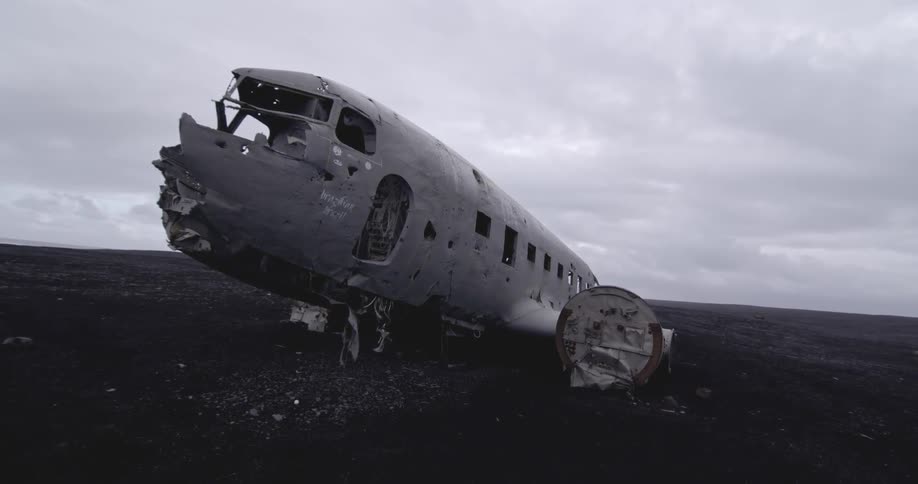 The plane is crashed apart on this field on a cloudy day
