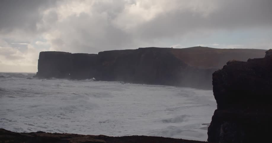 Ocean waves travel towards cliffs on a beach