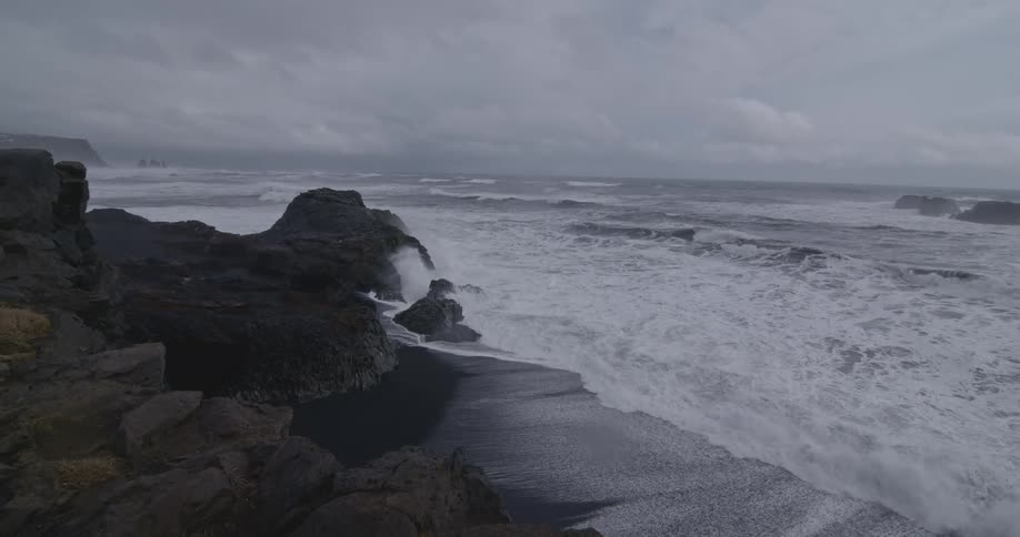 Waves roll ashore and crash against rocks on a stormy day