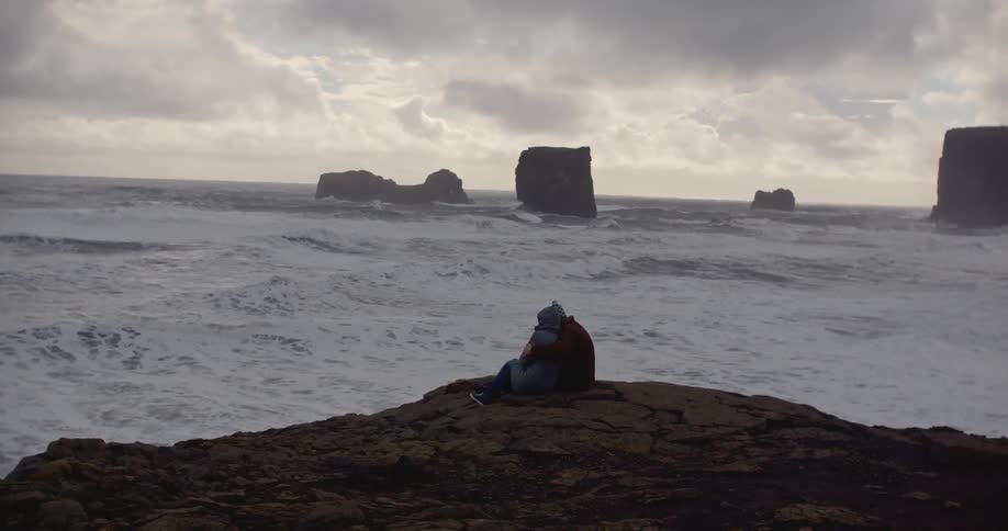 An embracing couple watch the waves roll in
