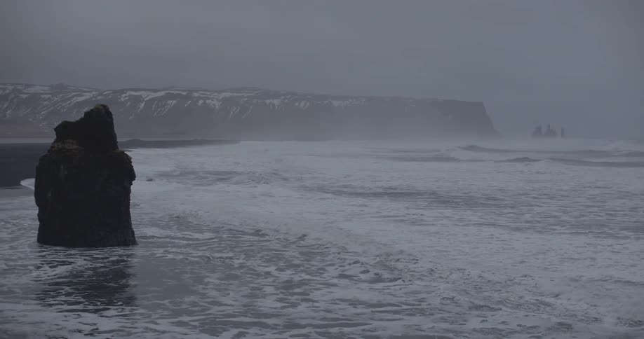 Ocean waves wash ashore on a misty day