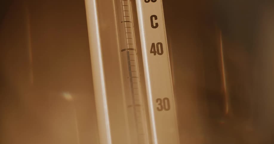 A thermometer with number markings and a liquid inside it is rising