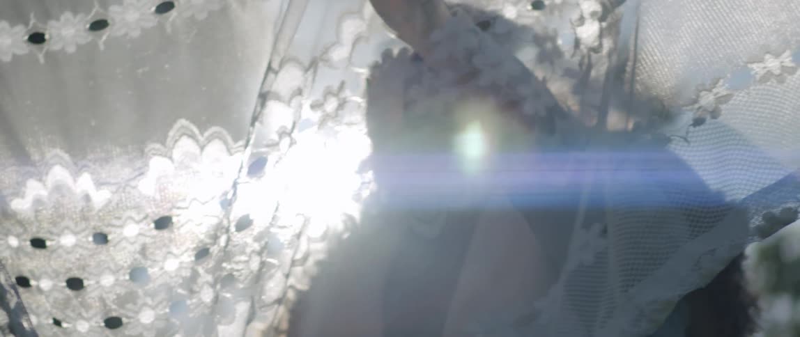 A person passing his hand over a white dress that is hanging