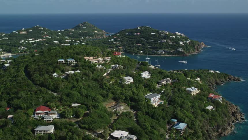 Aerial panorama of houses and hotels amid hills by the sea