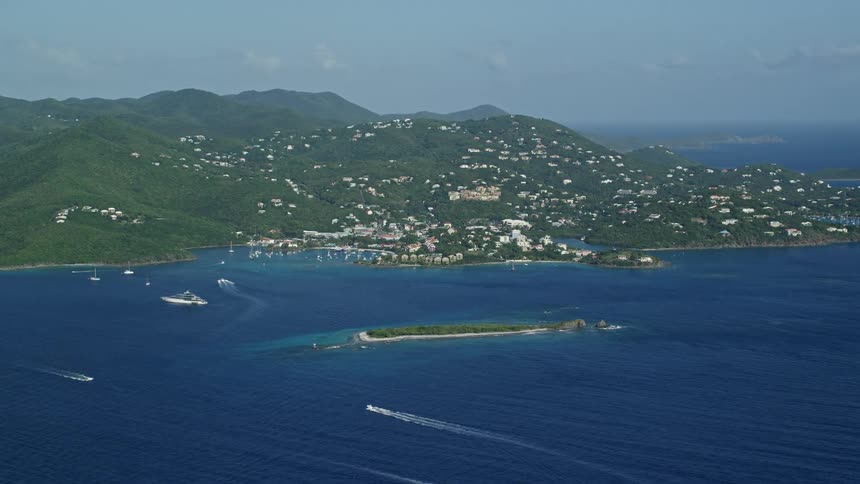 Aerial panorama of a peninsula with houses and boats moving in a blue sea