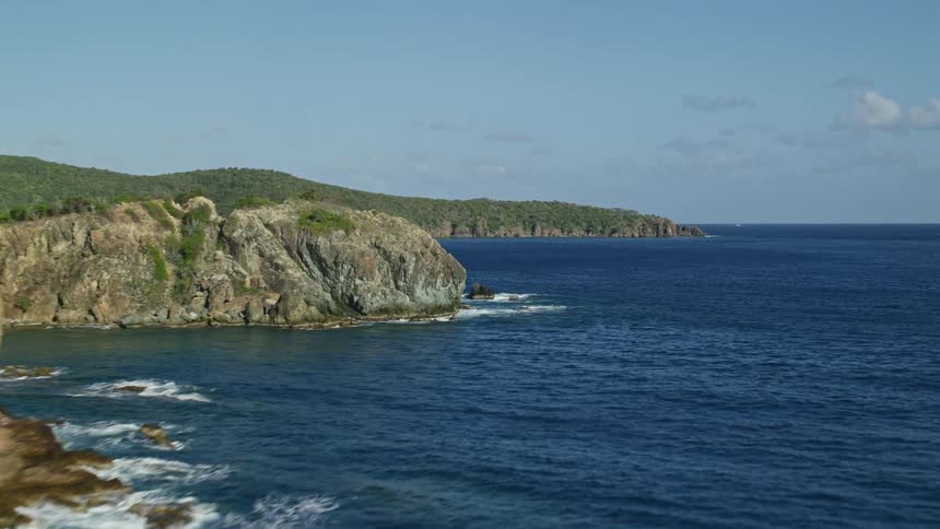 A coast of a land with high stone walls and the ocean that is very blue