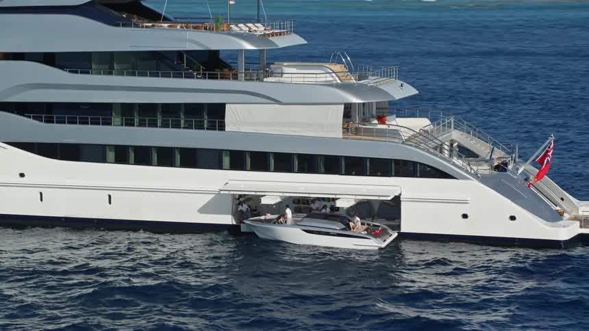 Aerial view of a huge yacht in the middle of the sea with a small boat next to it with people