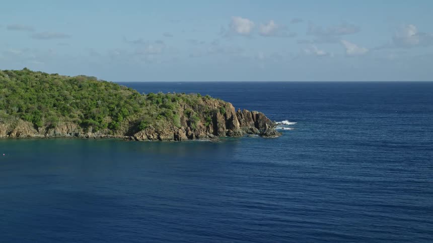 Aerial view of the coast facing the blue sea on a clear day with few clouds