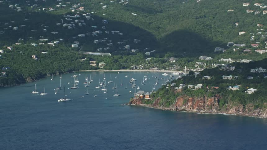 A bay by a beach is filled with various boats