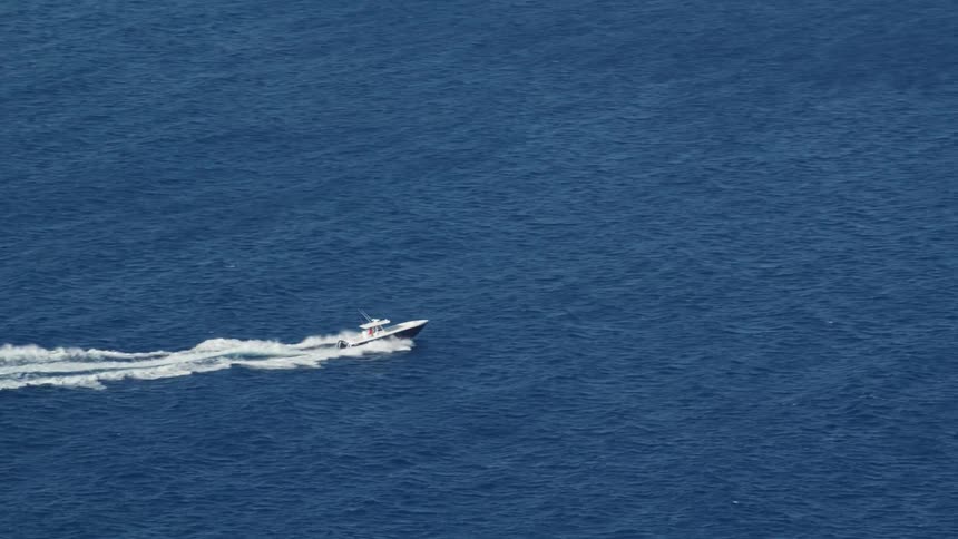 An aerial view of a boat skipping across the water