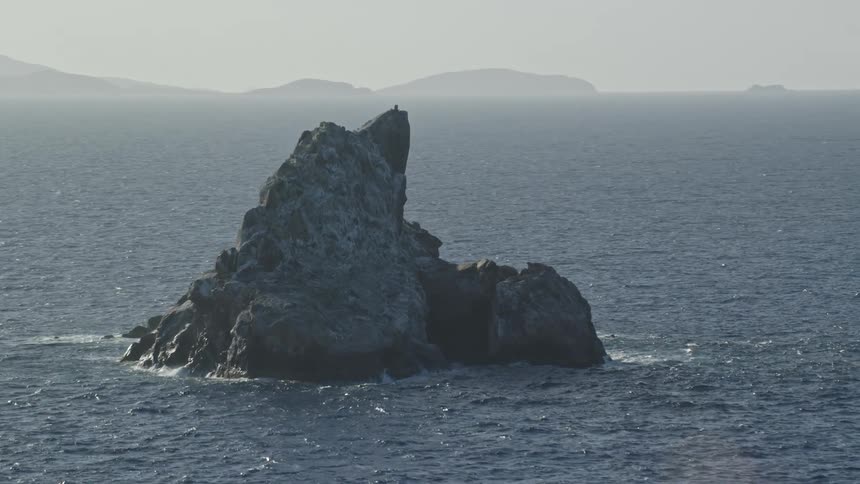 Aerial panorama of a rock in the middle of the sea in slow motion