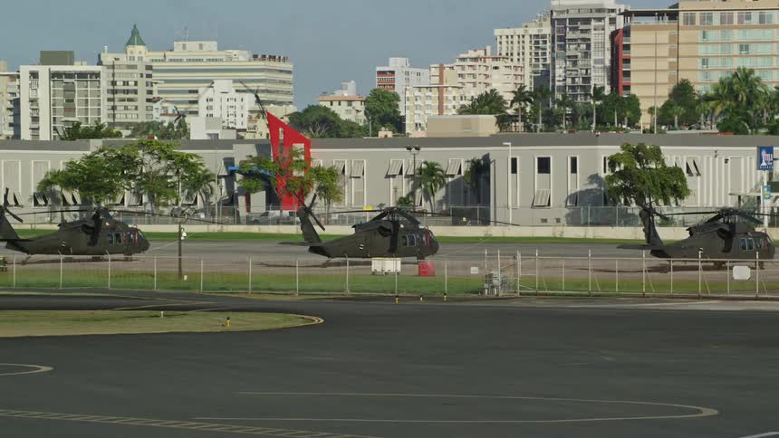 Three black helicopters sit at an airport