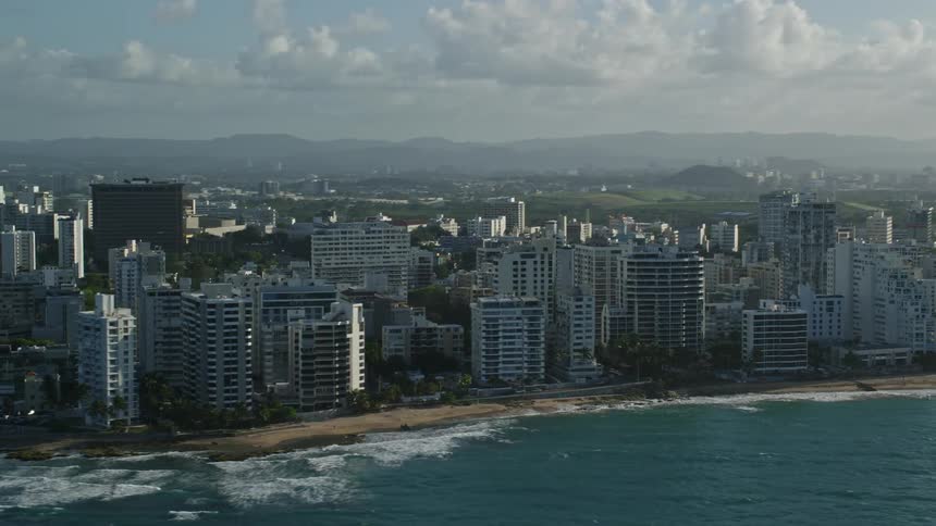 A coastal cityscape with numerous buildings lining the shore on a sunny day