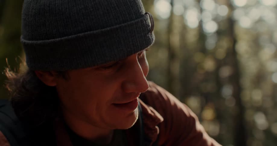 Man wearing beanie smiles in the forest
