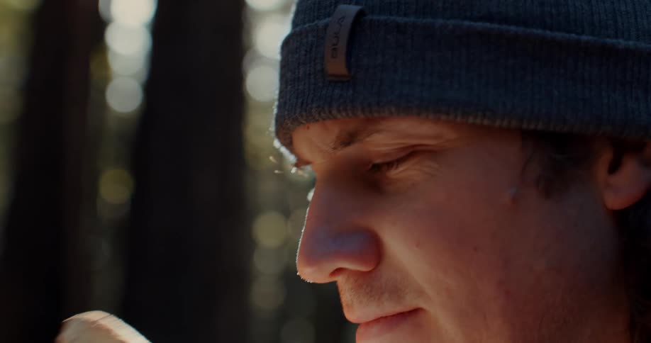 A man smelling a freshly picked mushroom in a forest