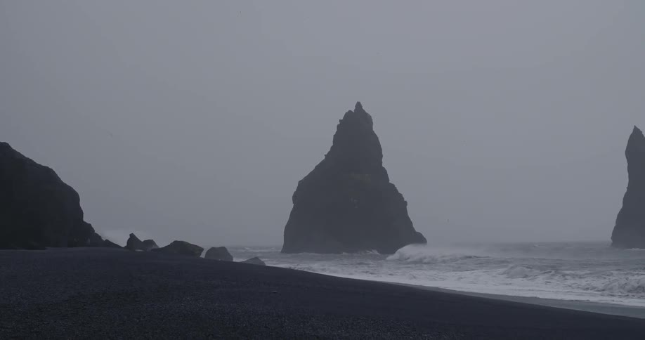 Large rocks jutting from the water near a beach
