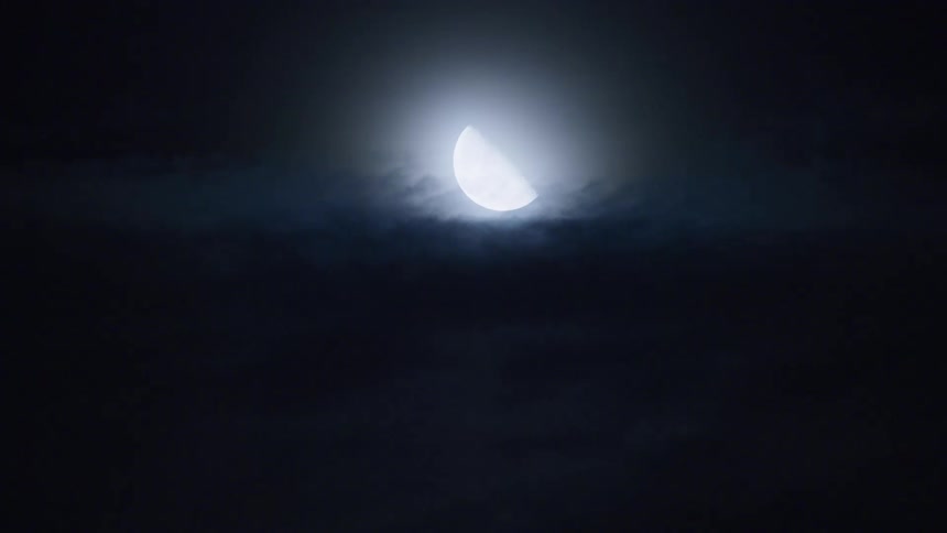 View of the moon with clouds passing by at night