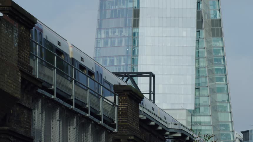 View of a train passing on an overpass with a glimpse of a towering building in a metropolis