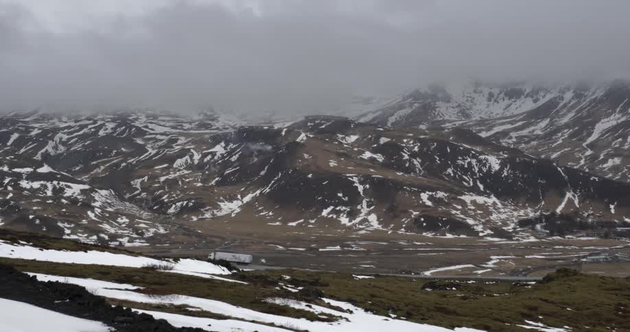 A big rig truck travels down a snowy mountain road