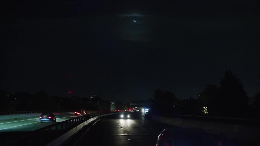 A freeway with some cars with headlights on driving at night