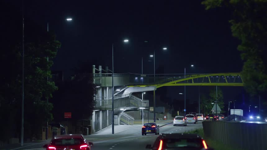 Traffic moves down a city road at night
