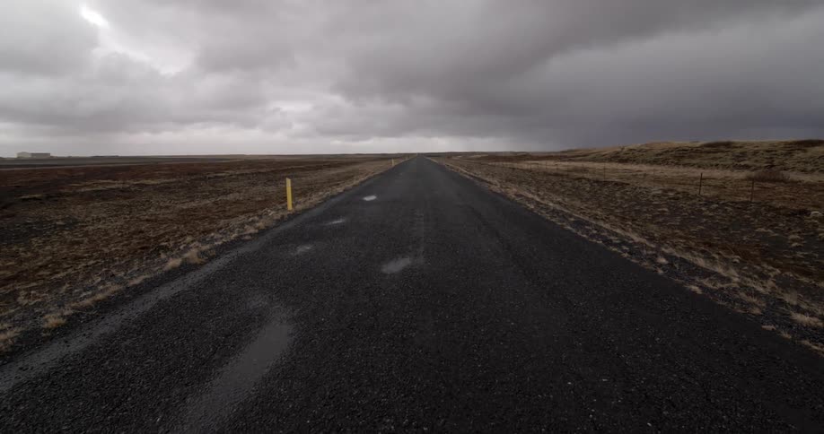 Storm clouds in the sky above a long dirt road