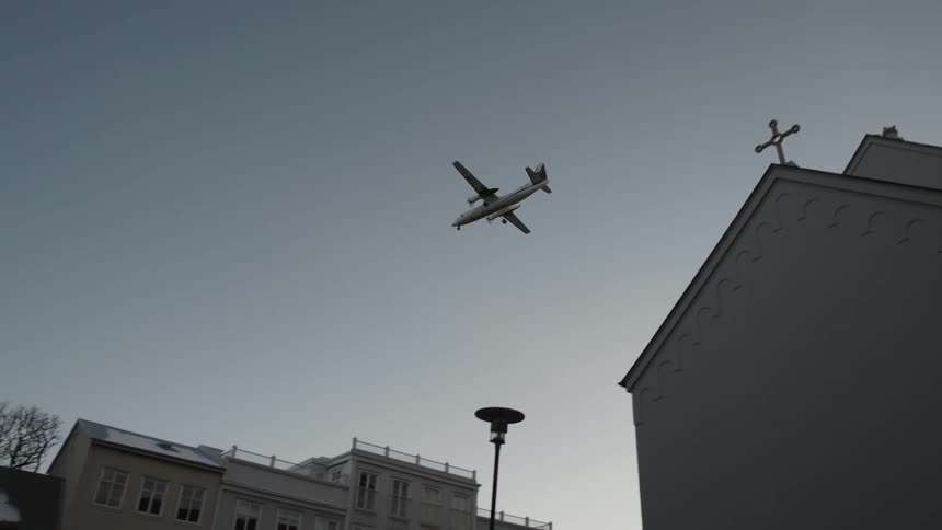An airplane flies above a church building