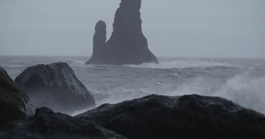 The water crashes against the rocks on a cloudy day