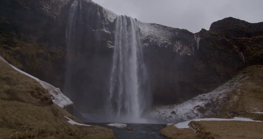 Water falls from a cliffside and flows down the mountain