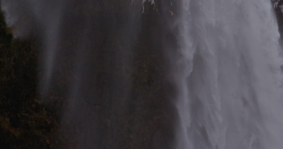 Water falls from a cliffside and flows down the mountain