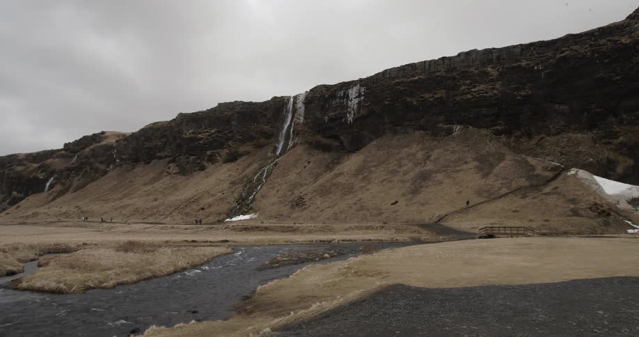 Water flows down a mountain cliffside and through a stream