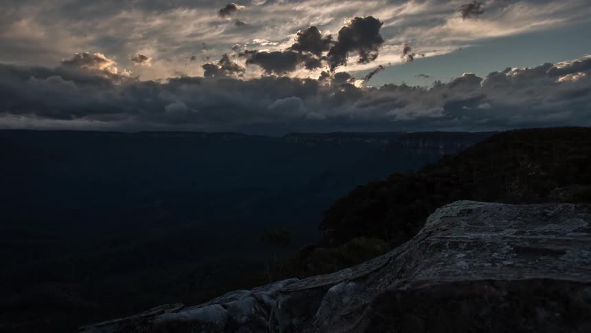 Clouds roll over a canyon as day turns to dusk