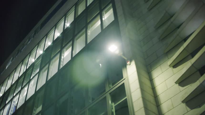 Upward view of the exterior of a mirrored building at night