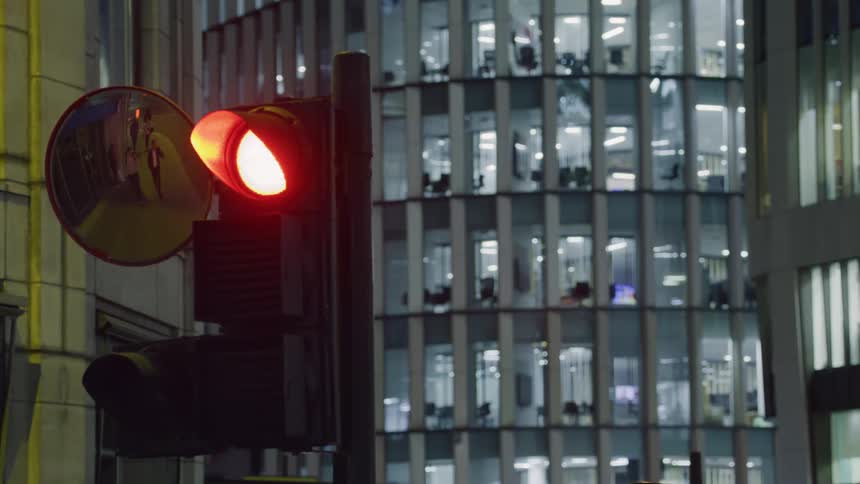 The mirror on the traffic light reflects people walking