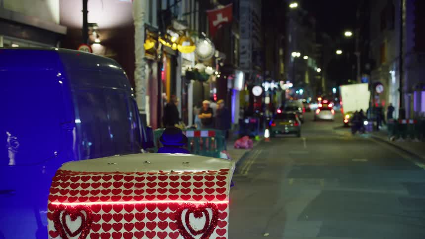 Pedicab travels along city street passing multiple businesses at night