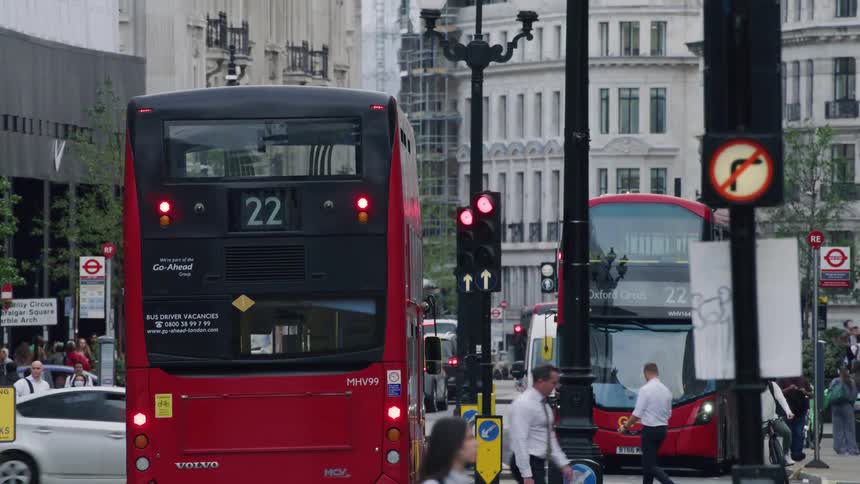 View of a street in the midst of a metropolis with people cars and buses passing by