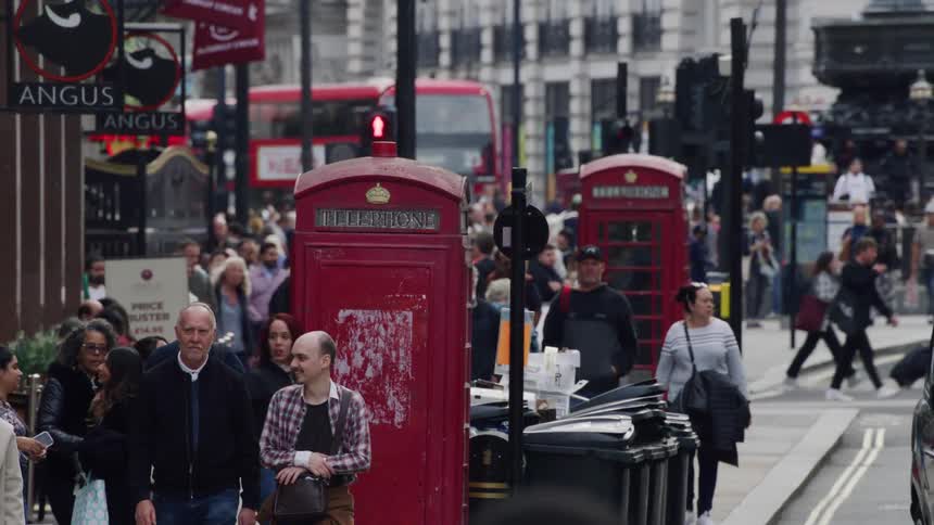 Street in the center of a busy city with people walking talking and private vehicles and public buses passing by