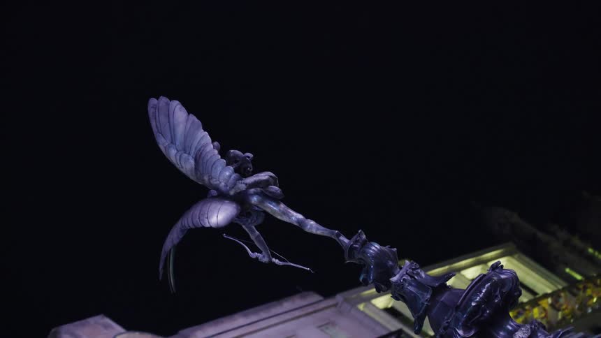 A winged statue sits near a tall building
