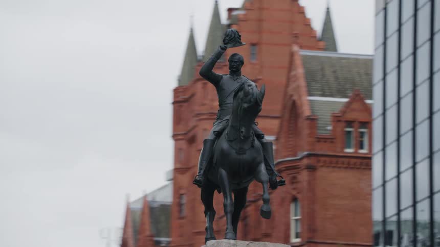 Monument of a man riding a horse in a square in the middle of a metropolis on a cloudy day