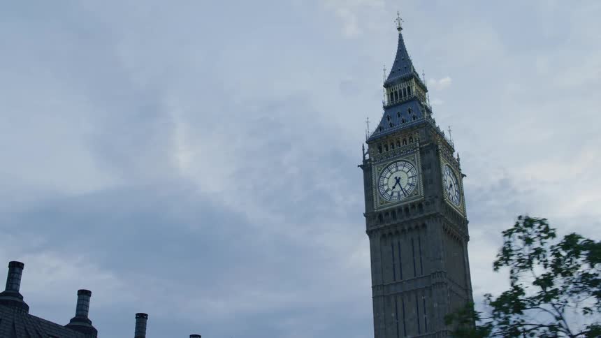 A clock tower of classical architecture in the city at sunset