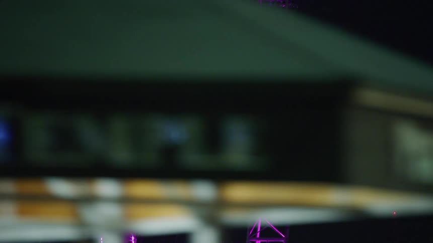The ferris wheel is lit purple at night