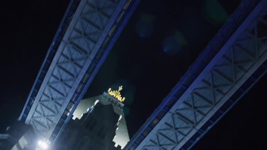 Upward view of a london bridge at night with purple lighting