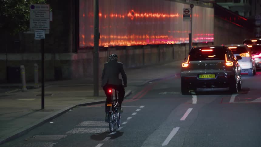 A person riding a bicycle in the city streets at night