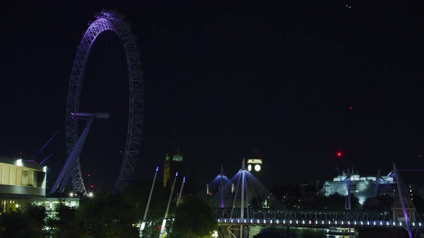 Panorama of the city of london with big ben a bridge skyscrapers and the illuminated ferris wheel at night