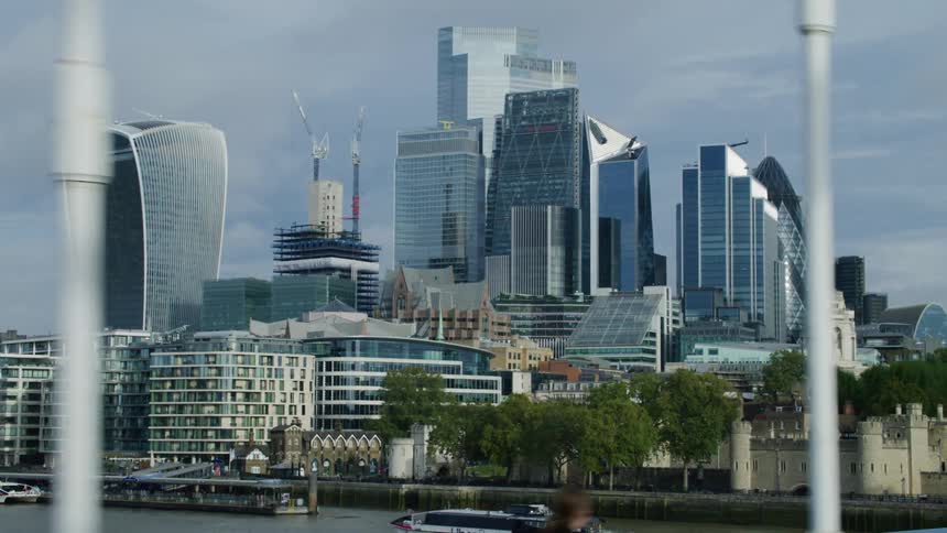 People walk across a bridge near a large city